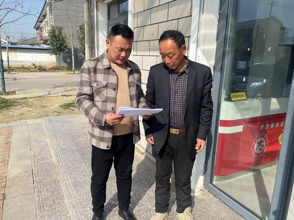 吴胜利（左一）向群众宣传土地流转相关政策.jpg